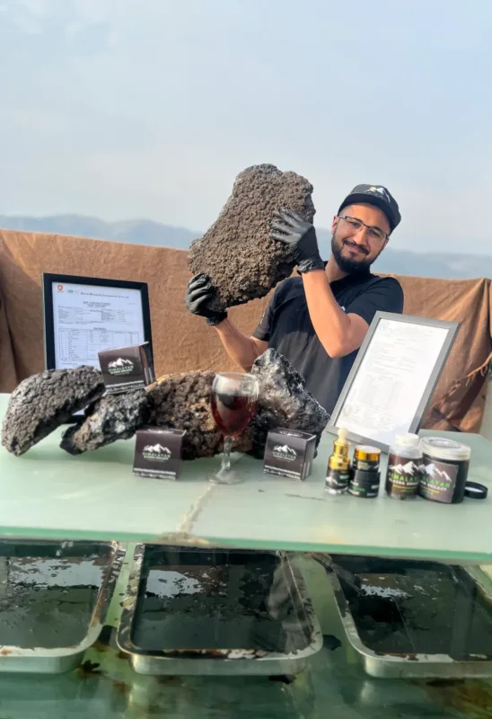 Elasna Himalayan Shilajit raw resin with team member, certificate, and finished premium products display