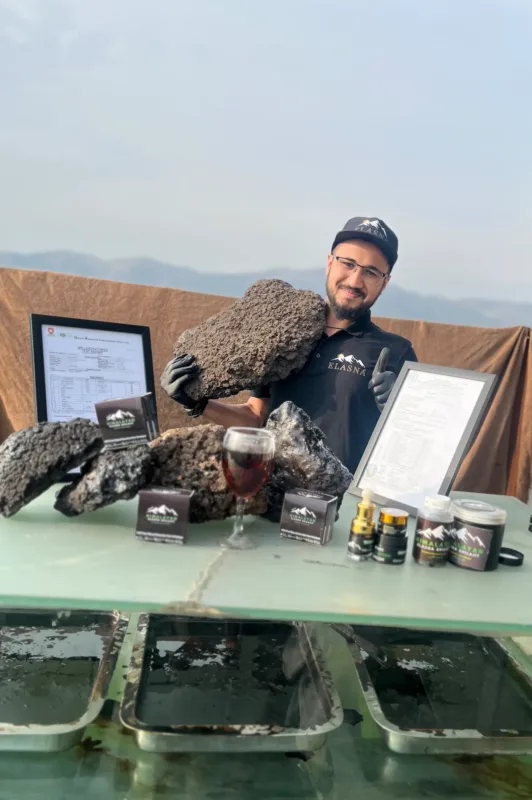 Elasna Himalayan Shilajit raw resin with team member, certification, and premium finished products display