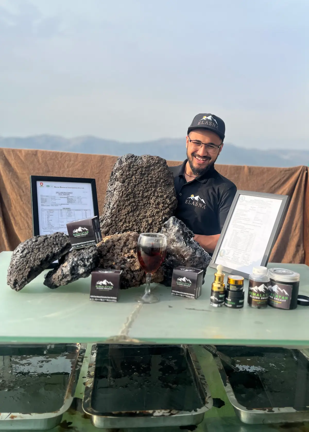 Elasna Himalayan Shilajit resin with team member showcasing raw extract and finished premium products